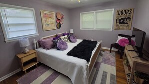 A bedroom with a bed, bedside tables, a lamp, a ceiling fan, and a poster on the wall.