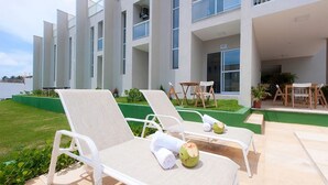 A modern hotel with white lounge chairs and a pool area. - Beach Townhouses I - Triplex by Carpediem (Aquiraz)