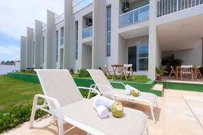 A modern hotel with white lounge chairs and a pool area. - Beach Townhouses I - Triplex by Carpediem (Aquiraz)