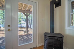 A room with a door leading to an outdoor area, a fireplace, and a window. - Peninsula Point - Five Bedroom Cottage, Sleeps 12 (Havelock)