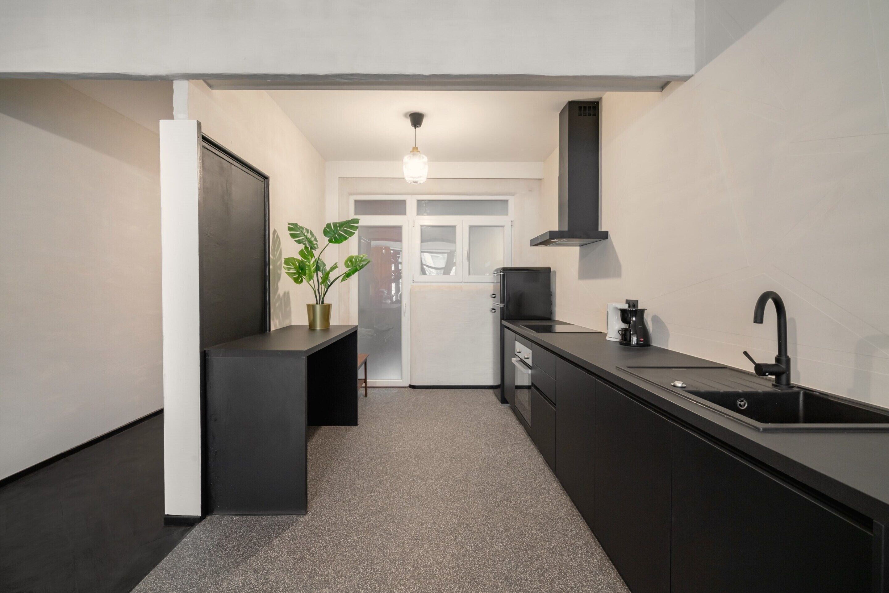 A modern kitchen with a black countertop, a sink, and a stove.