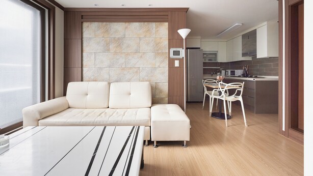 A modern living room with a sofa, a dining table, and a kitchen in the background.