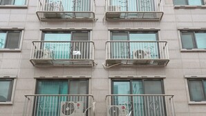 A multi-story building with balconies, air conditioning units, and a parking entrance.