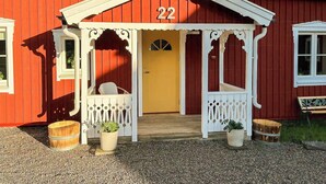 Ein rotes Gebäude mit weißem Wintergarten, Hausnummer 22, und zwei Blumentöpfen.