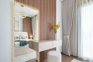 Ein modernes Schlafzimmer mit Bett, Nachttisch, Spiegel und Blick ins Freie.