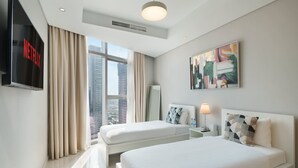 A hotel room with two beds, a TV, a painting, and a window with a city view. - Chic 2BR in Paramount Midtown Infinity Pool Access (Dubai)