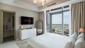 A hotel room with a large bed, a TV mounted on the wall, a balcony with a view, and a white dresser. - Chic 2BR in Paramount Midtown Infinity Pool Access (Dubai)
