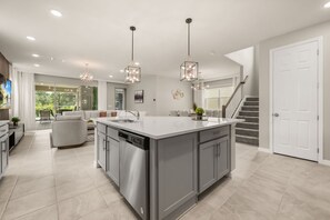 A modern kitchen with a central island, stainless steel appliances, pendant lighting, and a view to a balcony. - 7 BD/ 6 BA/ Solara Resort (1999 TP) (Kissimmee)