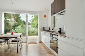 Eine moderne Küche mit weißen Schränken, einer Holzausziehtafel und einem Essbereich mit Tisch und Stühlen.