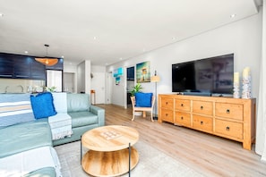 Ein modernes Wohnzimmer mit einer Couch, Couchtisch, Fernseher, Holzschrank und Kunstwerken an der Wand.