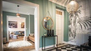 A hallway with a checkered floor, a console table with vases, a round mirror, and a wall with a tropical mural. - Modern villa with spa in the heart of Alsace (Selestat)