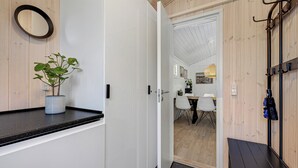 Un pasillo con una planta en maceta, un perchero y una puerta que da a un comedor.