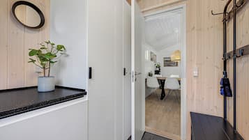 Un couloir avec une plante en pot, un porte-manteau et une porte donnant sur un coin repas.
