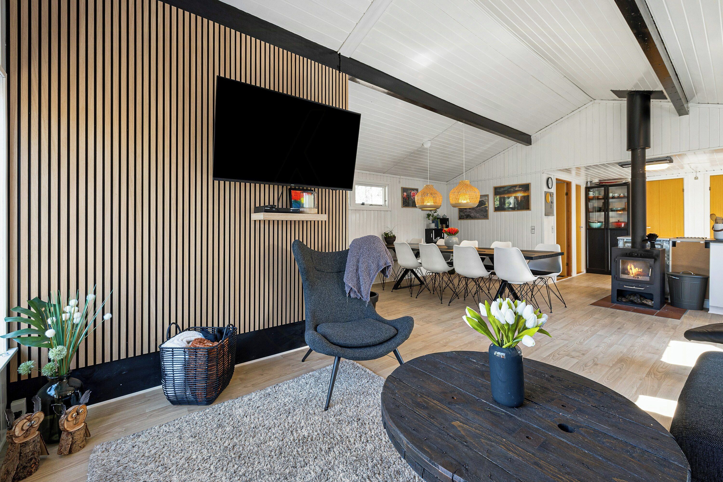 Un salon moderne doté d’un téléviseur à écran plat, d’une table ronde en bois et d’un coin salon confortable.