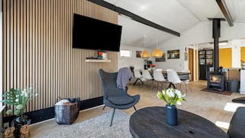 Un salon moderne doté d’un téléviseur à écran plat, d’une table ronde en bois et d’un coin salon confortable.