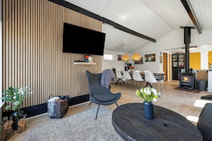 A modern living room with a flat-screen TV, a round wooden table, and a comfortable seating area. - Idyllic gem on Als Odde with activities (Hadsund)
