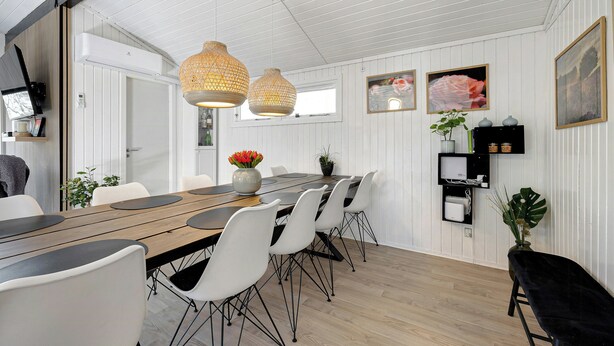 Comedor con una mesa de madera, sillas blancas y luces colgantes.