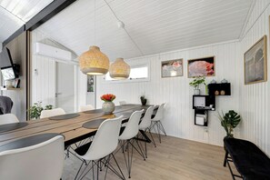 A dining area with a wooden table, white chairs, and pendant lights.