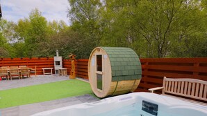 Een hottub, een houten vat, buiten zitplaatsen en een omheind gebied met bomen.