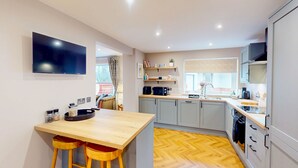 Een moderne keuken met een houten tafel, barstoelen, een ingebouwde oven en een raam met uitzicht.