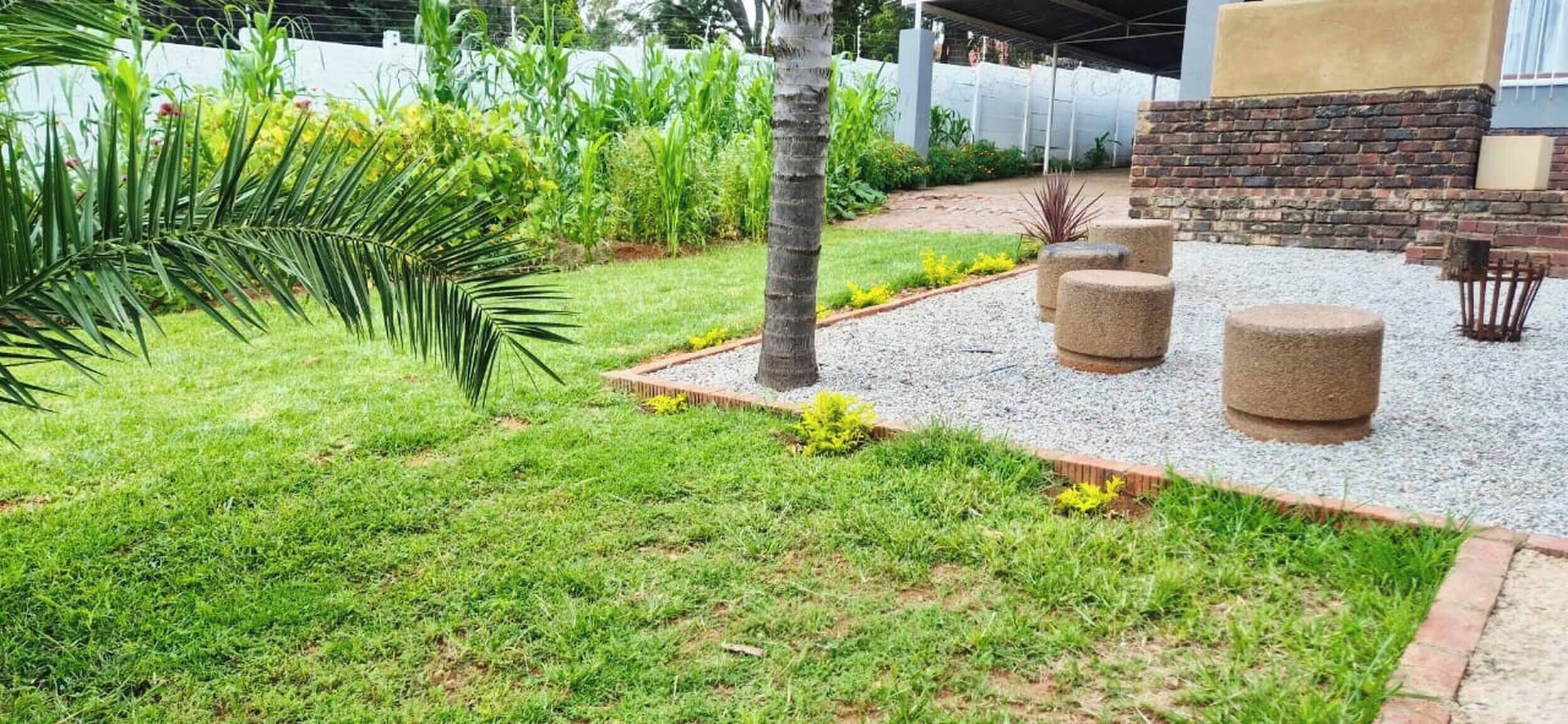 A landscaped garden with a palm tree, a brick wall, and outdoor seating.