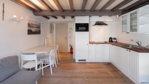 A kitchen with white cabinetry, a wooden countertop, and a built-in oven. There is a dining area with a table and chairs, and a gray sofa. - Spacious 11-person Stay in Antwerp (Antwerp)