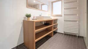 A bathroom with a wooden vanity, a mirror, a sink, a potted plant, and a radiator. - Spacious 11-person Stay in Antwerp (Antwerp)