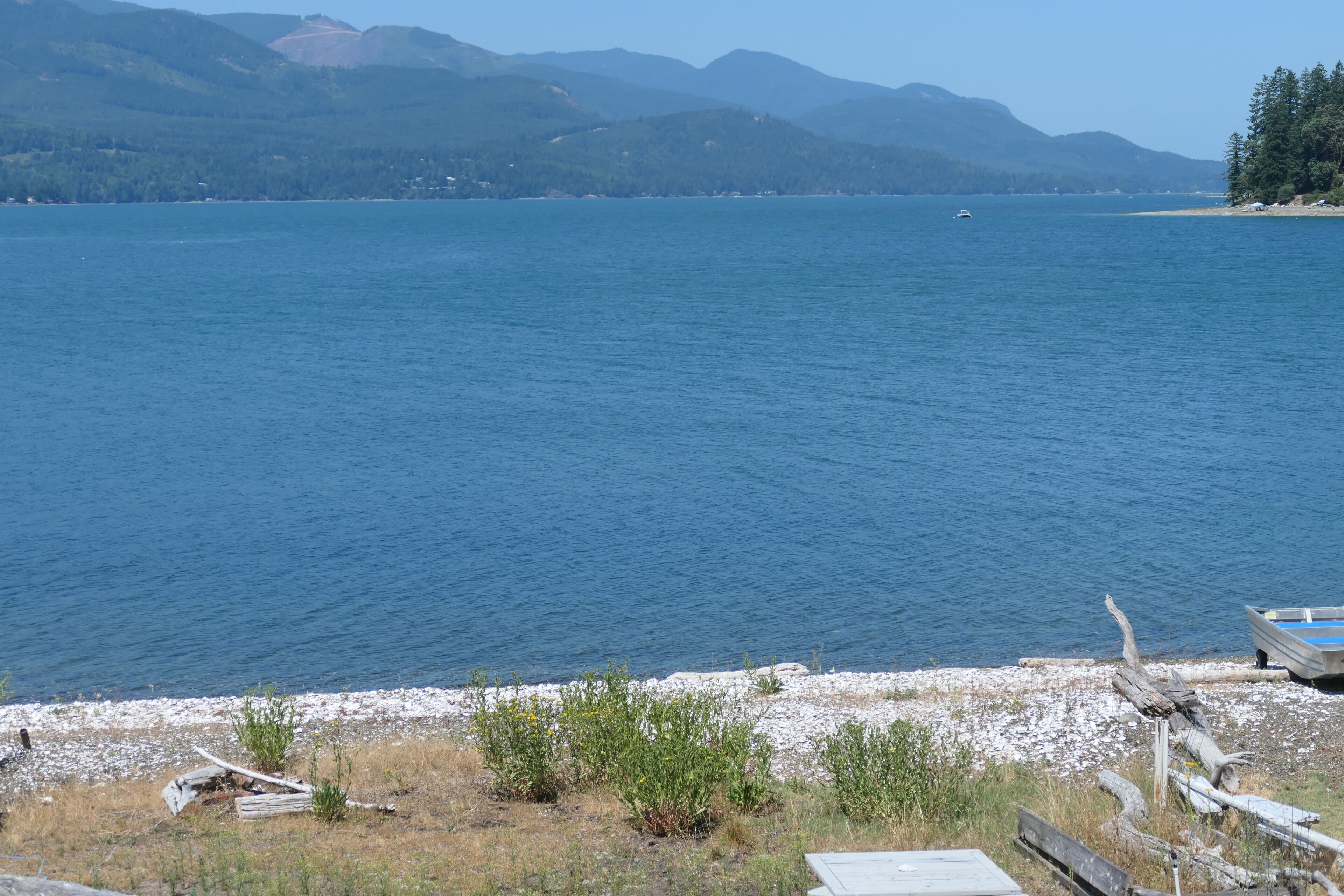 Un lac avec des montagnes en arrière-plan, une jetée en bois et un petit bateau.