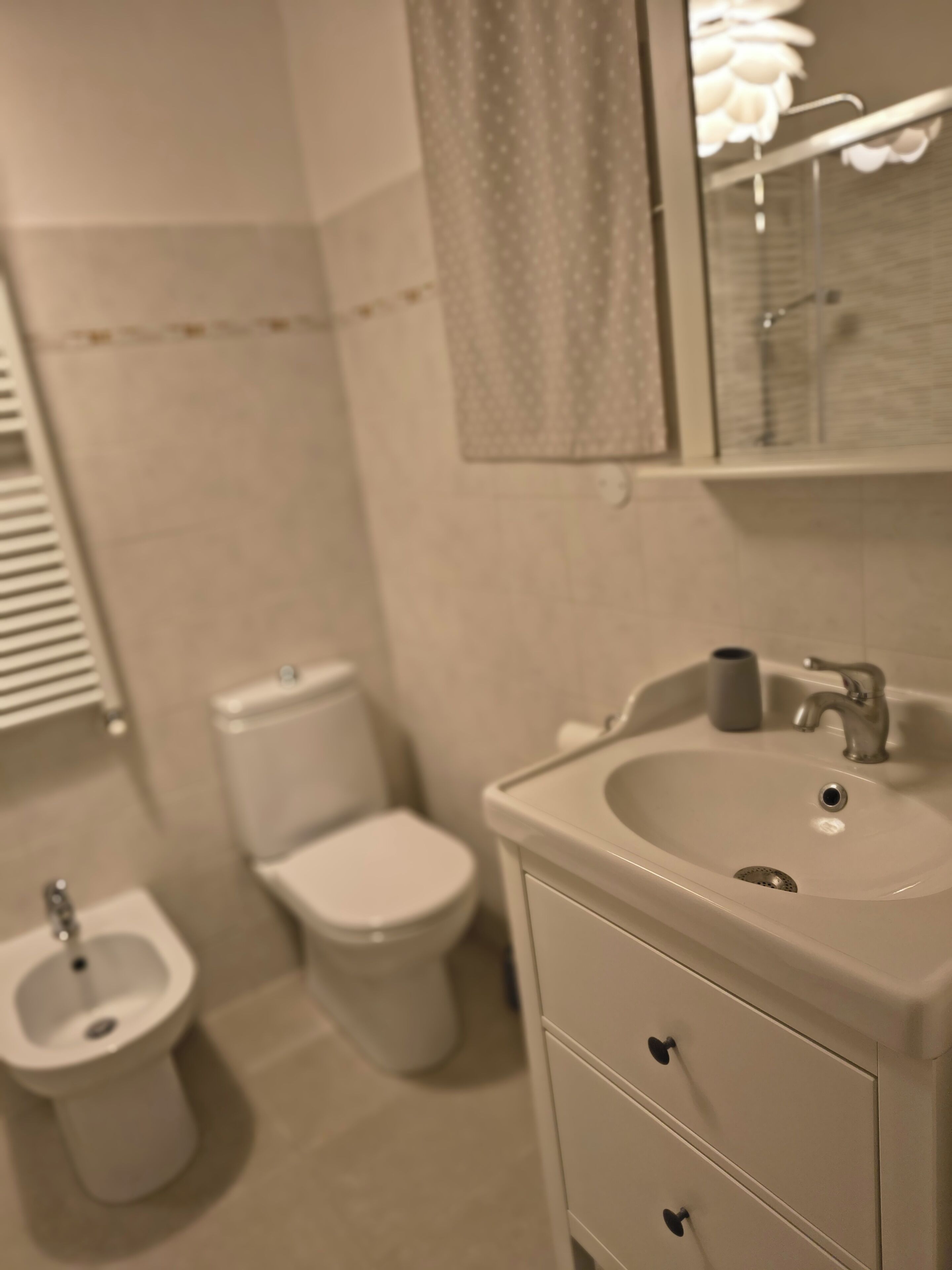 Un baño con inodoro, bidé, lavabo y espejo.