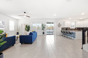 A spacious living area with a sofa, a dining table, and a kitchen with bar seating. - Resort included~Heated Pool~Game Room~Near Disney (Davenport)