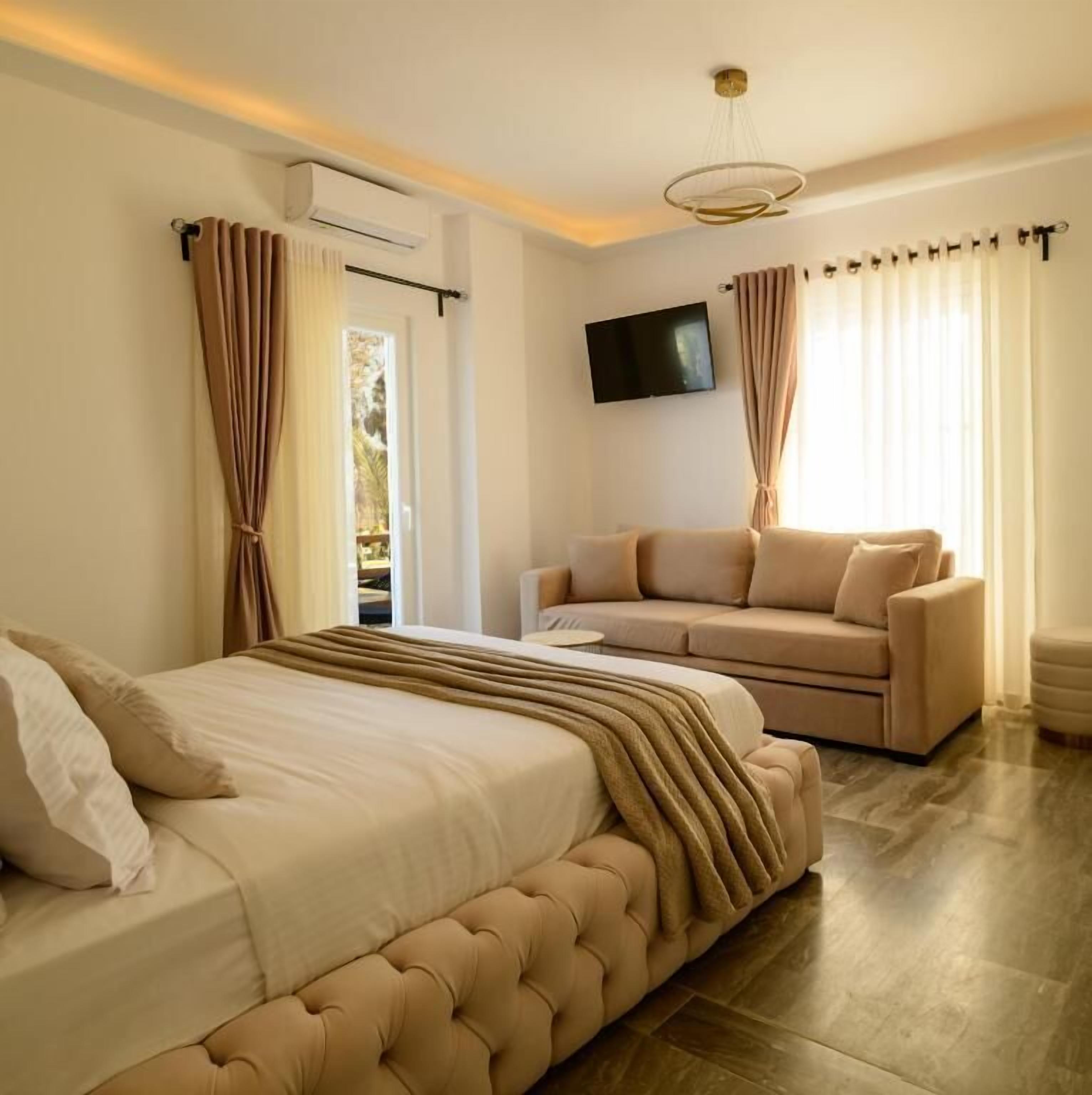 Een slaapkamer met een bed, een sofa, een televisie en een airconditioning.