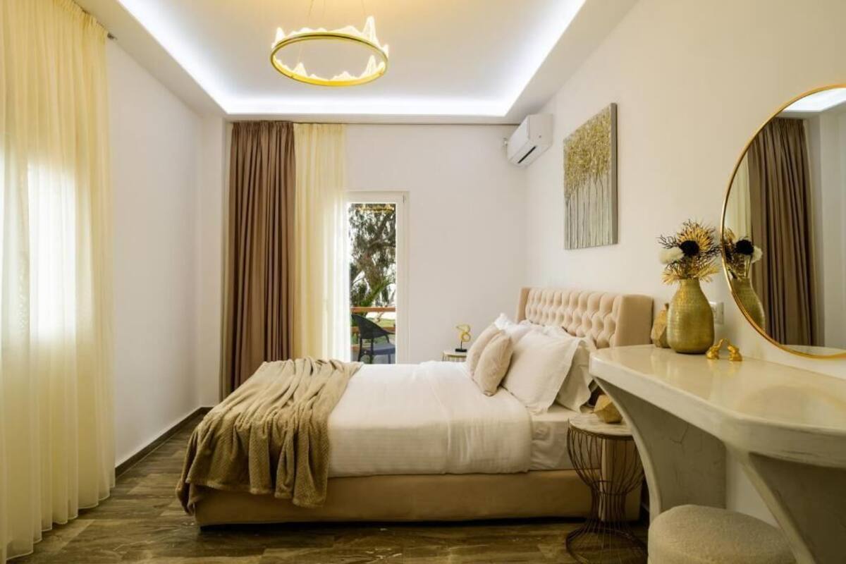 Un dormitorio con cama, mesita de noche, espejo y vistas al exterior.