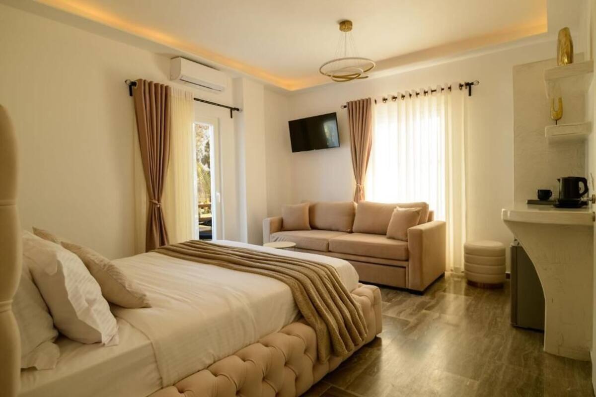 Un dormitorio con cama, sofá, televisor y kitchenette.