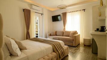 A bedroom with a bed, a sofa, a TV, and a kitchenette.