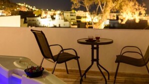 Eine Dachterrasse mit Whirlpool, zwei Stühlen und einem Tisch mit Getränken.
