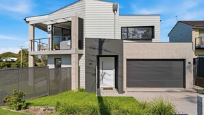 A modern two-story house with a balcony, a garage, and a well-maintained lawn. - Panoramic Point by Experience Jervis Bay (Vincentia)