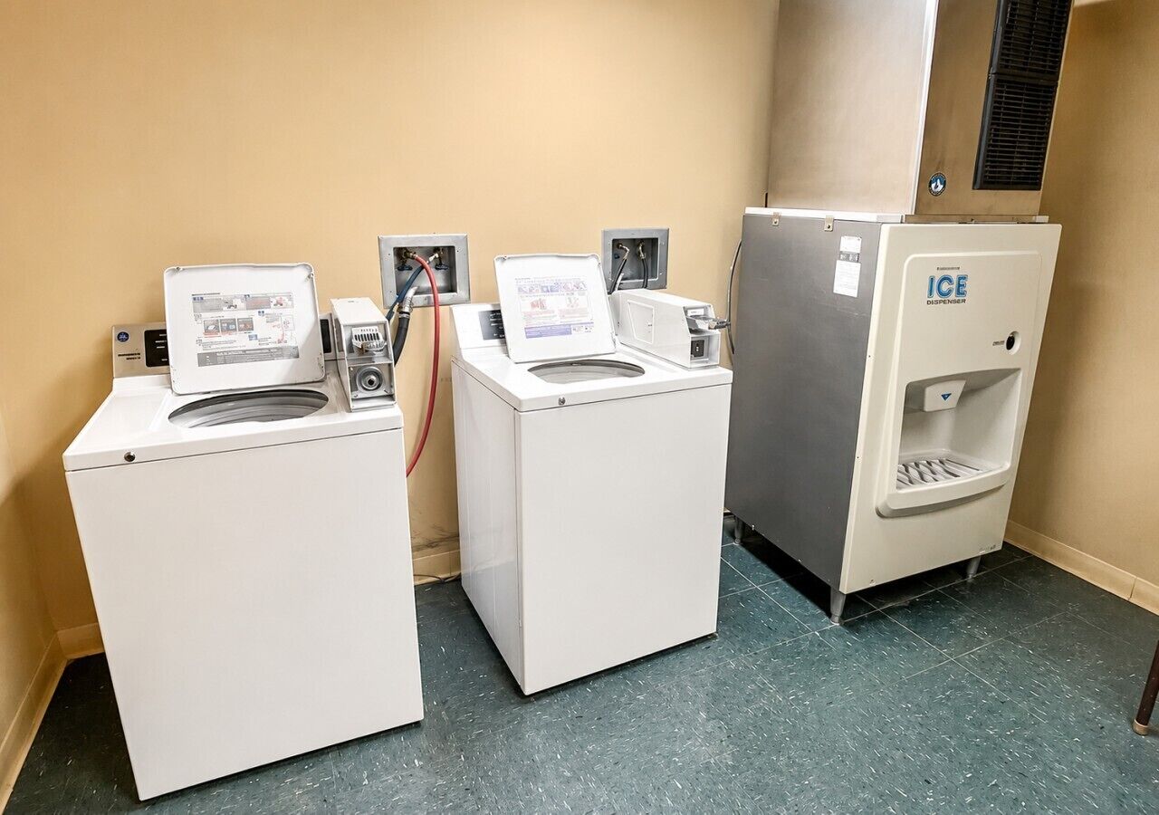 A laundry facility with three washing machines and an ice dispenser.