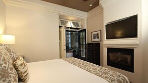 Quarto com cama, lareira, televisão e porta para área externa.