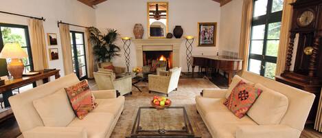 Un amplio salón con dos sofás, una mesa de centro, una chimenea y un ventanal grande.