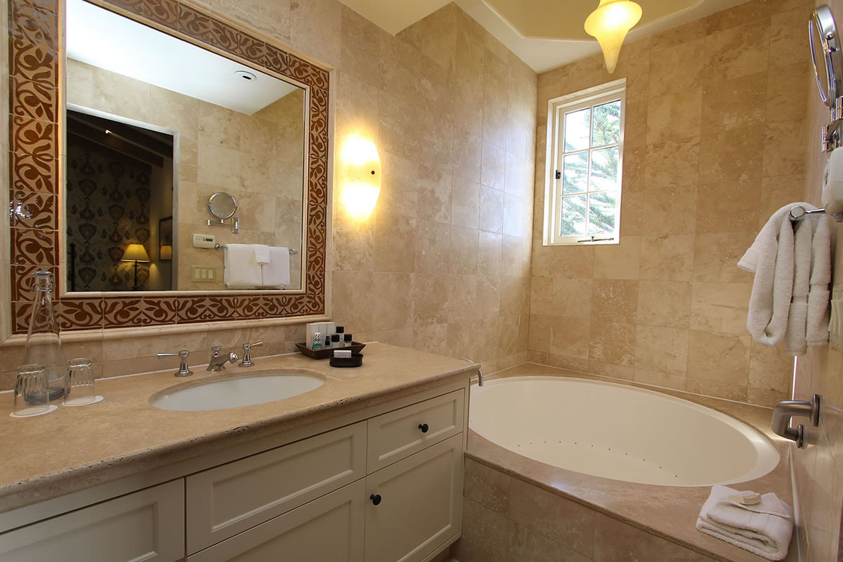 A bathroom with a double sink vanity, a large mirror, a bathtub, and a window providing natural light.