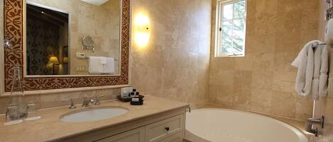 A bathroom with a double sink vanity, a large mirror, a bathtub, and a window providing natural light.