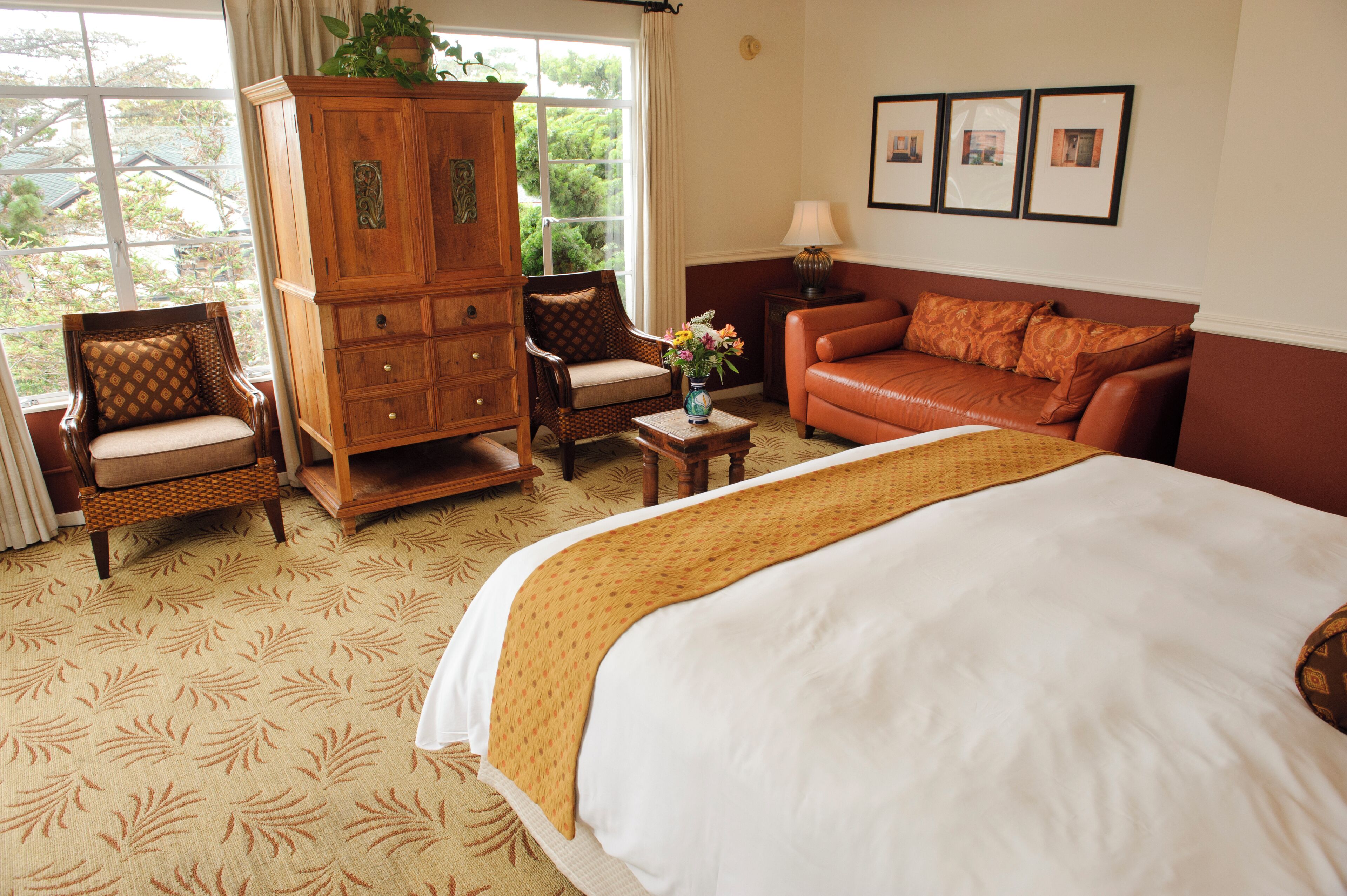 A hotel room with a large bed, a wooden cabinet, a sofa, and a chair.