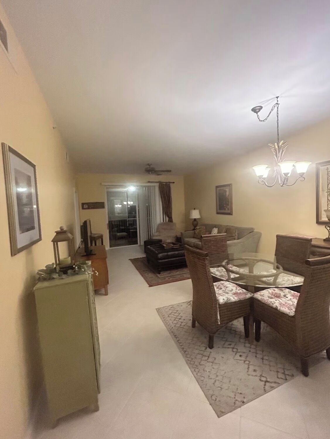 A living room with a glass coffee table, wicker chairs, a sofa, and a television.