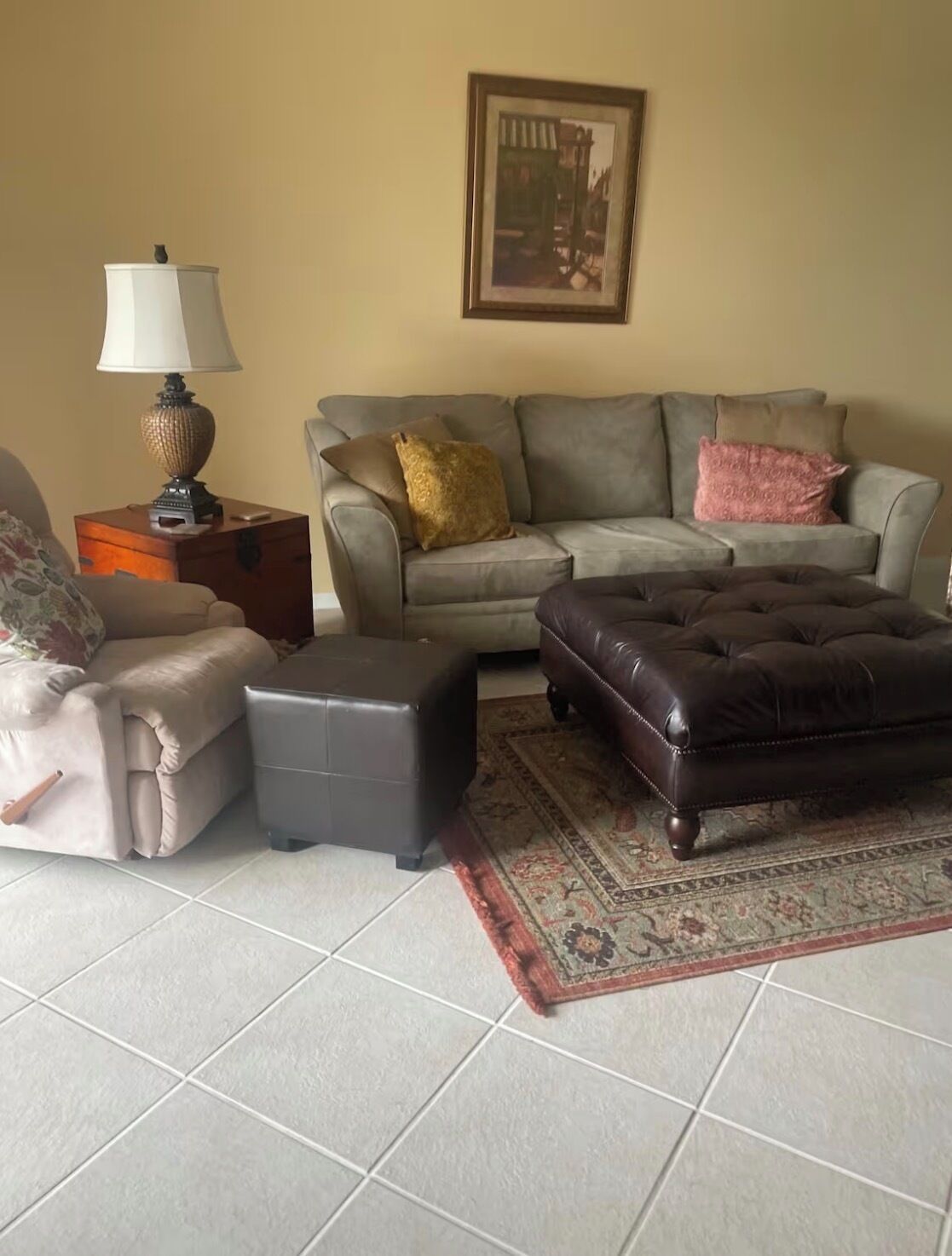 A living room with a sofa, two ottomans, a lamp, and a rug.