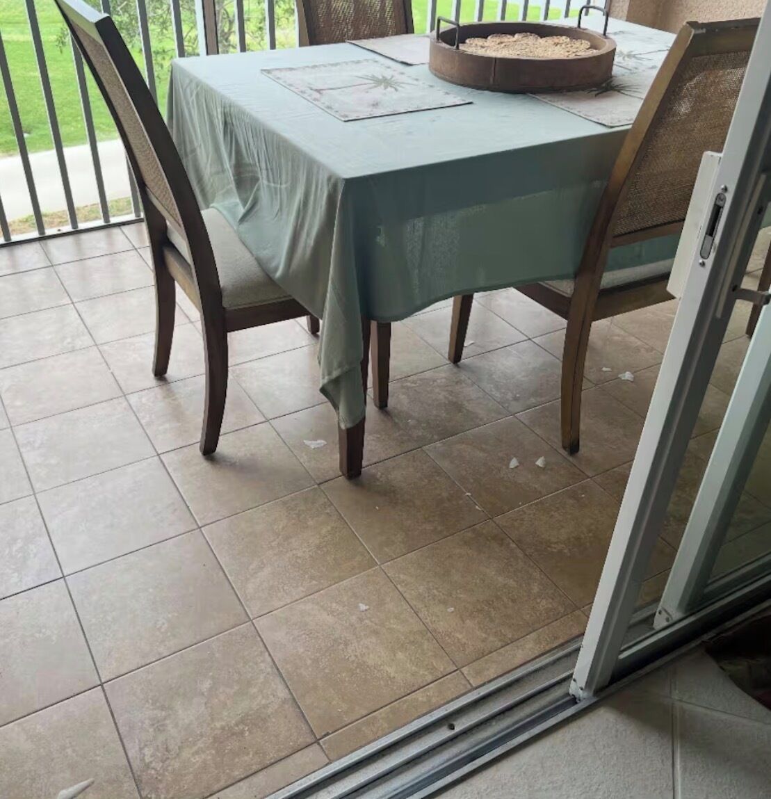 Une table à manger avec des chaises, un saladier en métal et un espace extérieur aménagé avec vue sur la verdure.