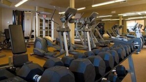 Un gimnasio con diferentes máquinas de ejercicio, incluyendo cintas de correr, elípticas y pesas libres.