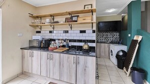 Una cocina con armarios de madera, una encimera con electrodomésticos y un área de lavandería.