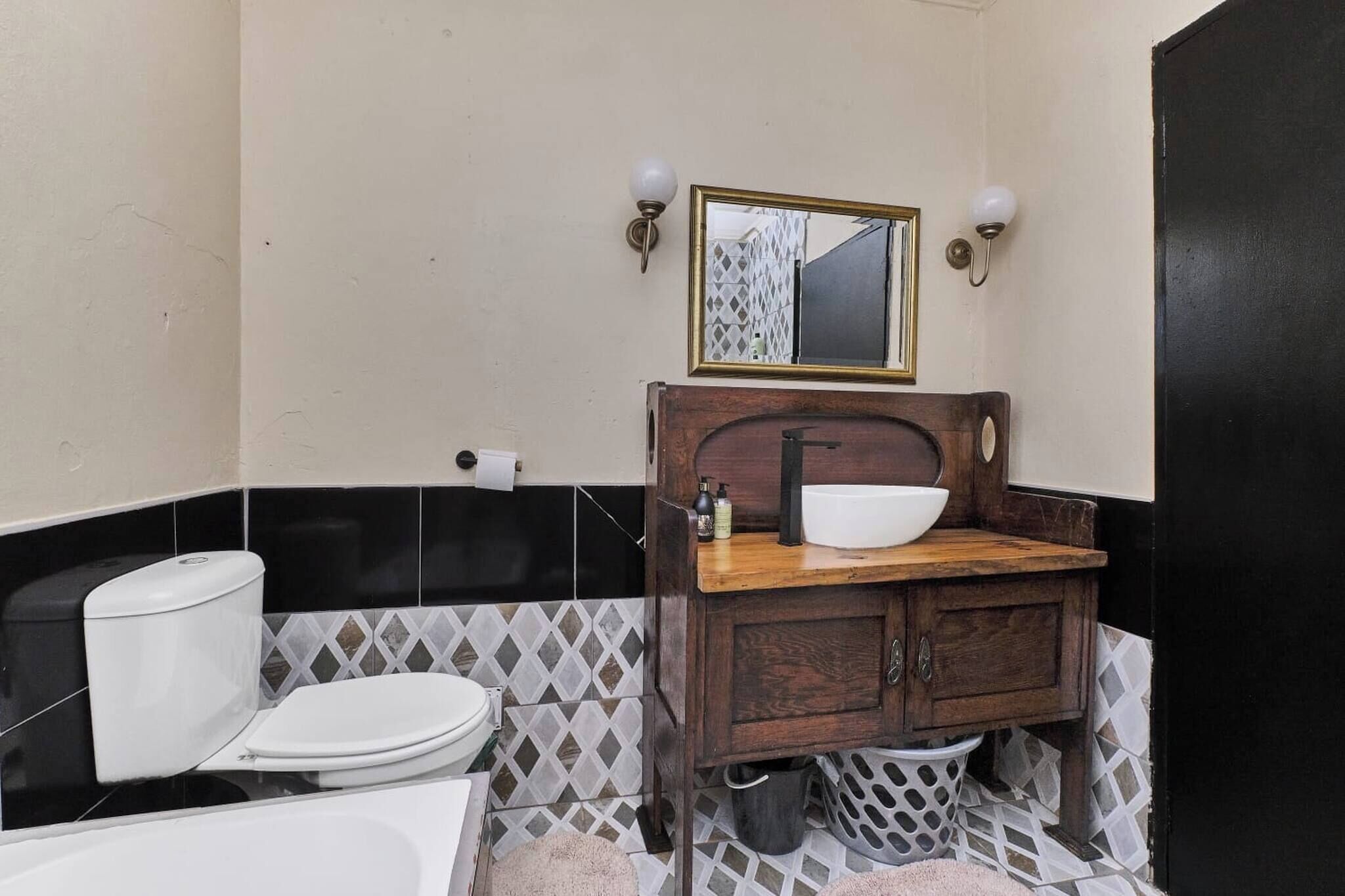 Un bagno con WC, lavandino, specchio e parete rivestita di piastrelle bianche e nere.