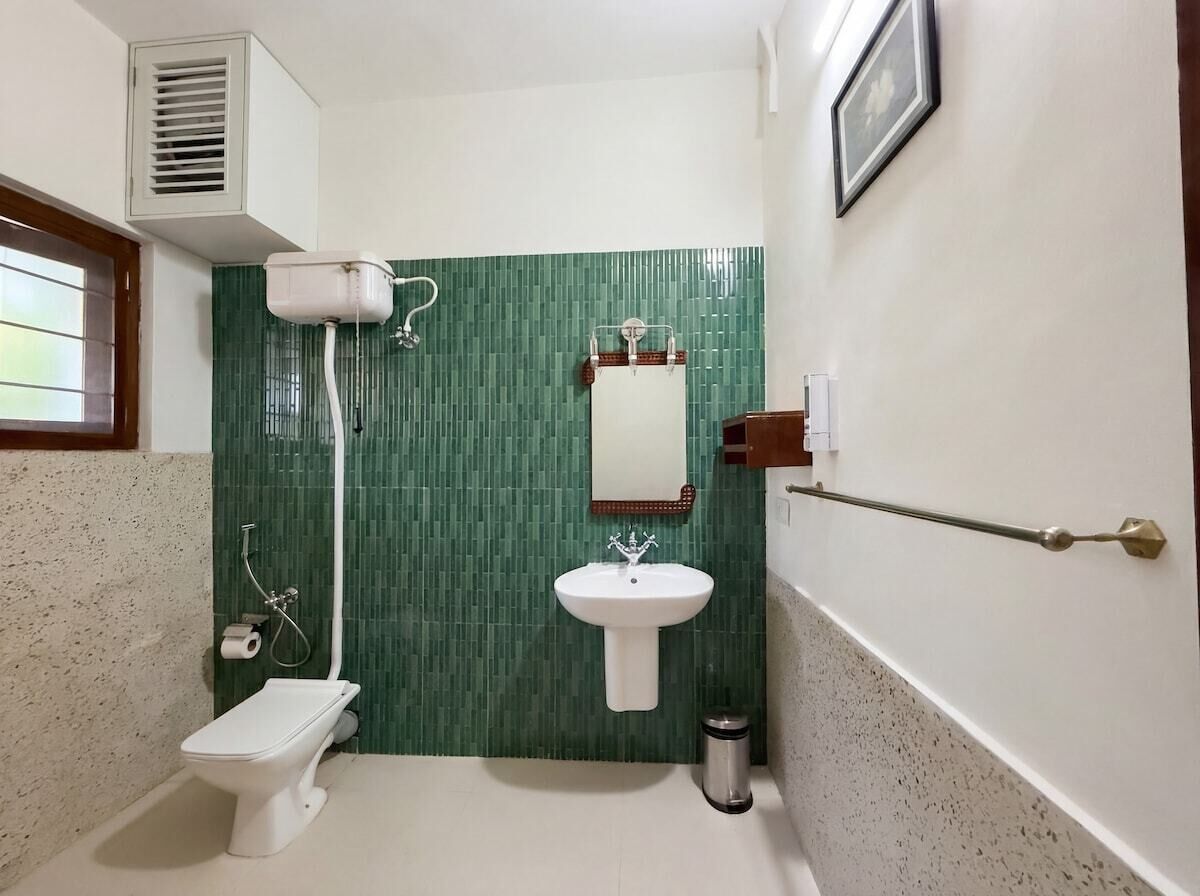 Un baño con inodoro, lavamanos, ducha y unidad de ventilación.