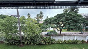 A view of a residential area with a paved road, parked cars, and greenery including trees and bushes. - Himalaya 6BHK bungalow with AC in Mysuru (Mysuru)